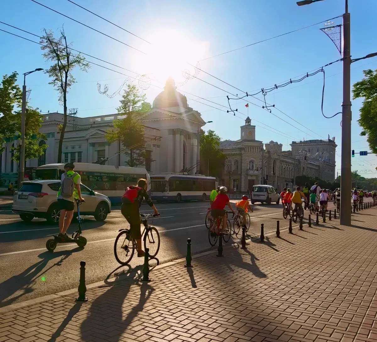 Bicicliști și un trotinetist pe un bulevard din Chișinău, în fața Primăriei.